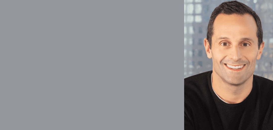 Professional portrait of a smiling man with a blurred city background, suitable for a corporate profile or business banner