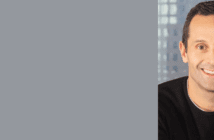 Professional portrait of a smiling man with a blurred city background, suitable for a corporate profile or business banner