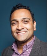 Professional portrait of Gautham Narayanan, Managing Director of VIRTUE Europe, smiling at the camera against a dark blue background.